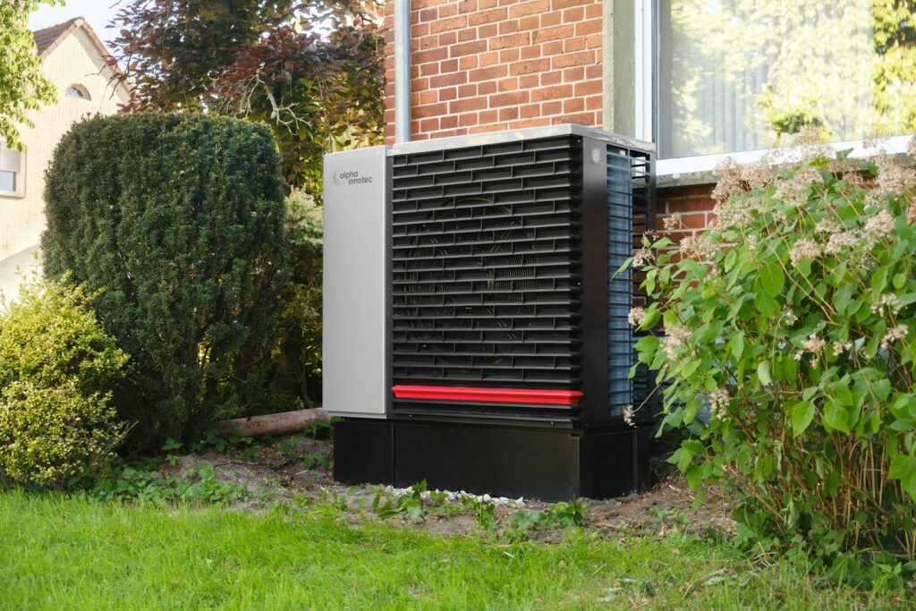 Buitenunit van een lucht-waterwarmtepomp naast een bakstenen woning